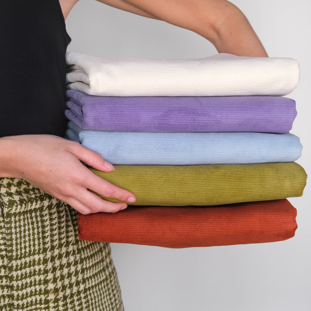 Person holding stack of fine cotton corduroy
